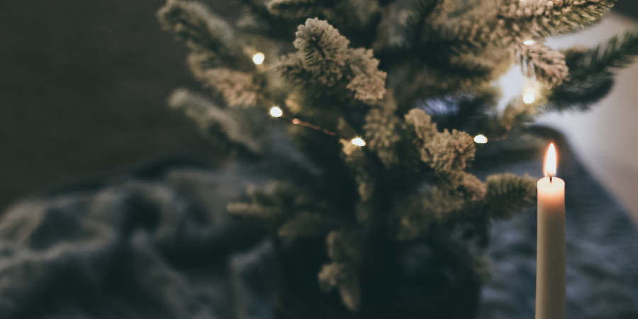 Une bougie qui brille devant un sapin