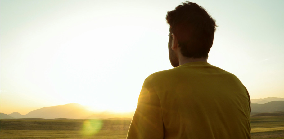Un homme en prière devant un lever de soleil