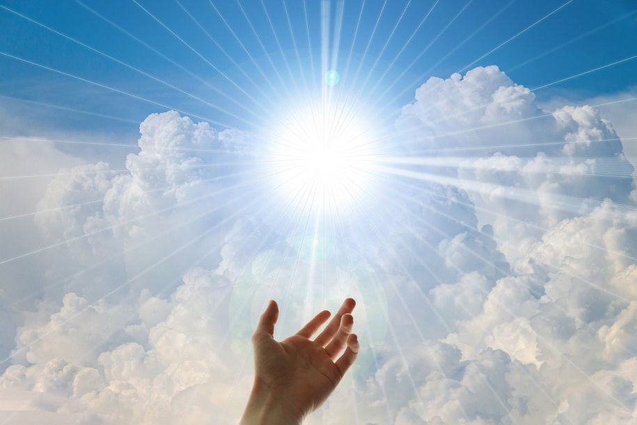 Une main qui se tend vers un ciel où le soleil brille