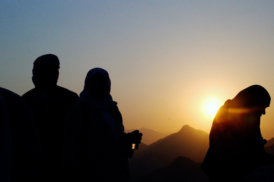 Des personnes qui prient devant un coucher de soleil