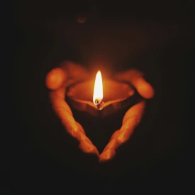 Une bougie dans des mains. La foi est fragile comme cette flamme de bougie