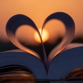 Un livre qui dessine un cœur avec un coucher de soleil en arrière plan