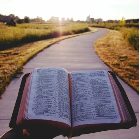 Une bible ouverte sur une route qui passe entre deux champs