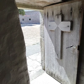 Une porte en bois ouverte avec un croix de la chapelle du manoir du tourbe